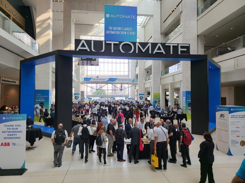 People gathered for a netwroking event in a hall at Automate 2023.